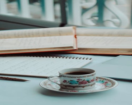 A cup of coffee on a desk with notebooks